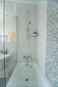 a white bathroom with a shower and a sink at Station Suites in Watford