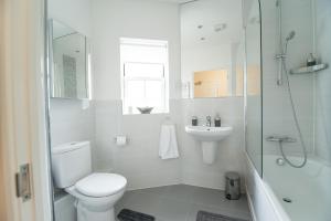 y baño con aseo, lavabo y ducha. en Station Suites en Watford