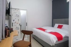 a bedroom with a bed and a desk and a chair at RedDoorz Syariah near UNIMUS Semarang in Alastuwo