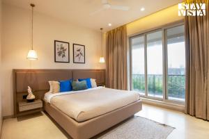 a bedroom with a bed and a large window at StayVista at Solace Land with Bonfire, Jacuzzi in Lonavala