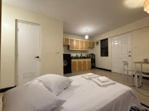 ein großes weißes Bett in einem Zimmer mit Küche in der Unterkunft Rosewood Stay Taguig Flat in Rosewood Pointe near BGC and the Airports in Manila + 19 Fotos
