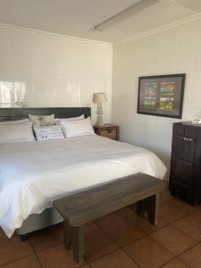 a bedroom with a large bed with a bench on it at Karoo Huisie in Vanderbijlpark +6 photos