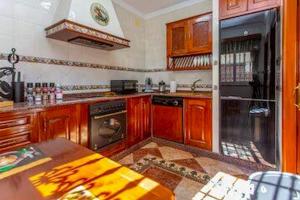a kitchen with wooden cabinets and a stove top oven at Villa Stella maison entre Séville et Cadix in Lebrija