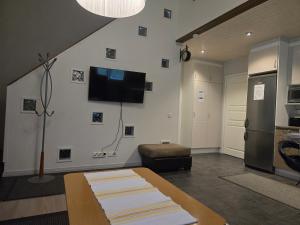 a living room with a table and a tv on the wall at Majoituspalvelu Nurmi Oy Välitie 3B Saunallinen in Raahe