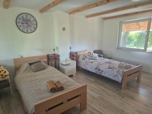 a bedroom with two beds and a clock on the wall at Vikendica na Tisi in Ada