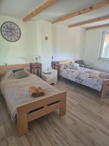 a bedroom with two beds and a clock on the wall at Vikendica na Tisi in Ada