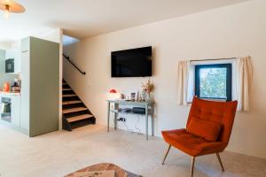 un salon avec une chaise orange et un bureau dans l'établissement La Grangerie, à Moulézan