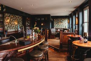 a pub with a bar with stools and tables at Landhotel Kauzenberg in Bad Kreuznach