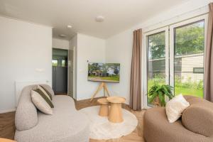 a living room with two couches and a large window at Panorama wellnesslodges x Vakantiepark Hölte in Rijssen