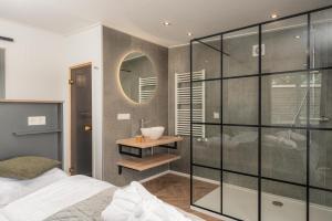 a bedroom with a shower and a sink and a mirror at Panorama wellnesslodges x Vakantiepark Hölte in Rijssen +28 photos