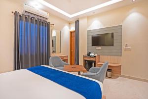 a hotel room with a bed and two chairs and a television at The Prominence Hotel Restaurant & Bar in Greater Noida