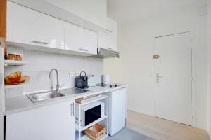 Una cocina blanca con fregadero y estufa. en Modern Studio Moderne - 2P - Rueil-Malmaison, en Rueil-Malmaison 2 fotos más