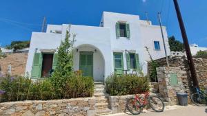 a white house with a green door and a bicycle at Spice Suites-Lime in Amorgos