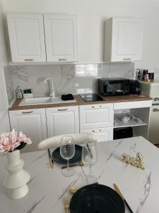 a kitchen with white cabinets and a table with wine glasses at Suite Secrète in Sélestat