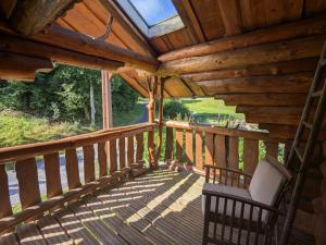 eine Veranda einer Hütte mit einem Stuhl darauf in der Unterkunft Fuste insolite avec balcon et terrasse dans les Vosges - FR-1-589-241 in Le Tholy