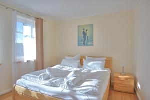 a white bed in a bedroom with a picture on the wall at Strandvilla Börgerende in Börgerende-Rethwisch