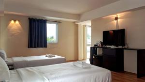 a hotel room with two beds and a flat screen tv at VS Beach Front in Jomtien Beach