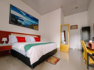 SiborongborongNoah Hotel Silangit的一间卧室配有一张带红色和绿色枕头的大床