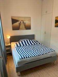 a bed with a blue and white striped blanket on it at Bright & friendly flat in downtown Duisburg - "Miner Mates Home" from revierquartier boutique apartments in Duisburg
