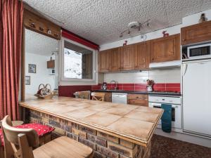 une cuisine avec une table en bois et un réfrigérateur blanc dans l'établissement Studio spacieux proche pistes, balcon, animaux admis - FR-1-502-424, à Tignes