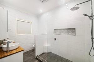 a white bathroom with a shower and a sink at Family Dream Home in Burpengary East +4 photos