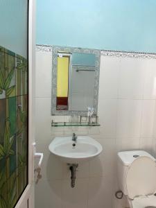 a bathroom with a sink and a toilet and a mirror at Hanh Thông Homestay in Dong Hoi