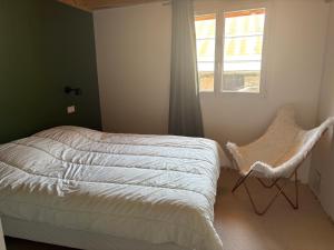a bedroom with a bed and a window and a chair at Chalet Belleville in Béranger +1 photo