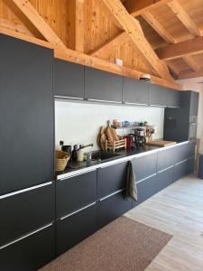 a kitchen with black cabinets and wooden ceilings at Chalet Belleville in Béranger