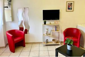 a living room with two red chairs and a tv at Studio Revy 4 - Confort et équipé - Centre ville in Néris-les-Bains