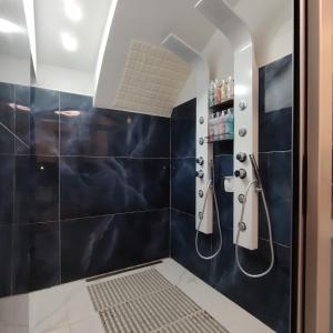 y baño con ducha de azulejos azules. en House 80palmi, en Catania