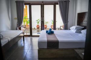a bedroom with two beds and a large window at Gili Ocean Club - ADULTS ONLY in Gili Trawangan