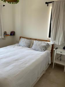 a bedroom with a bed with white sheets and a window at Tirza's Place in Livnim