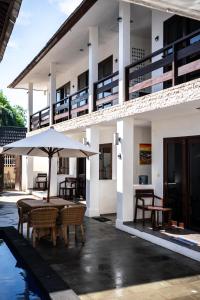 an outdoor patio with tables and an umbrella at Gili Ocean Club - ADULTS ONLY in Gili Trawangan