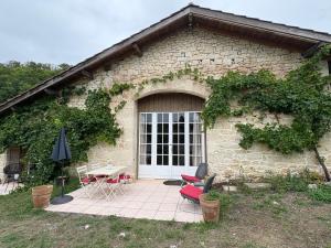 a stone house with a patio with chairs and a table at Las Coussoulesses in Anthé