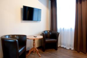 Pokój z dwoma krzesłami, stołem i telewizorem w obiekcie Apartamenty Hotelu Pod Orłem w Toruniu