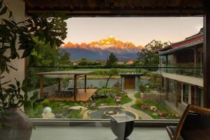 a balcony with a view of a garden and mountains at LiJiang Mountain Spring Resort in Baisha
