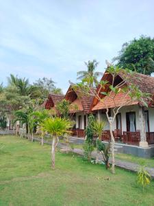 a house with palm trees in front of it at Santhi Guna Bungalow in Nusa Penida