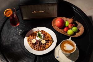 a table with a plate of waffles and a bowl of fruit at LiJiang Mountain Spring Resort in Baisha