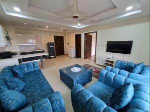 a living room with blue couches and a flat screen tv at Furnished apartments in Rawalpindi