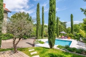 a pool in a garden with cypress trees at Les Vignes - Newly refurbished 18th century house with Mediterranean garden in Caluire-et-Cuire