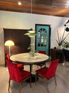 a dining room with a table and red chairs at Chic Designer Family Rooms in Shared Bungalow near LRT SS1 PJ in Petaling Jaya