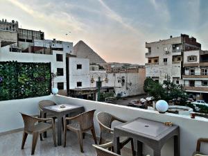 a balcony with tables and chairs and a view of the pyramids at Aladdin Sphinx & Pyramid Stay in Cairo