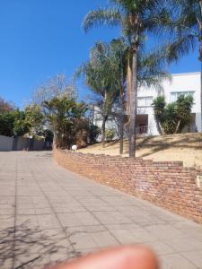a sidewalk with a brick wall and palm trees at A call for all guests in Pretoria