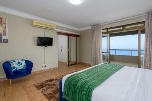 a bedroom with a large bed and a blue chair at Ya Rona Sea View -5 Bedroom Ramsgate Holiday Home KRB1 in Margate +57 photos