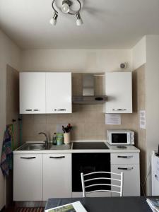 a kitchen with white cabinets and a sink and a microwave at Landscapesilvia PT Terra in Menaggio