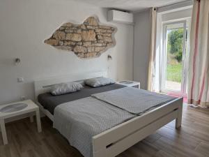a bedroom with a bed and a stone wall at House Carla Belavici in Hreljići