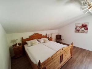 a bedroom with a wooden bed with white sheets at Ferienwohnung Goldfasan in Lam +26 photos