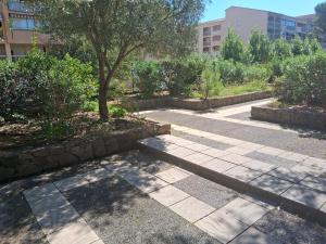 a walkway in a park with a tree and a building at Domaine du Préconil in Sainte-Maxime
