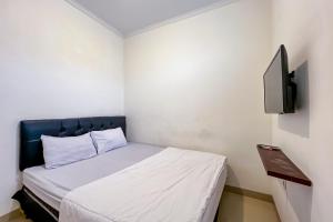 a small bedroom with a bed and a tv at JJ House Mitra RedDoorz in Jakarta