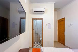 a room with a television and a bathroom with a toilet at JJ House Mitra RedDoorz in Jakarta